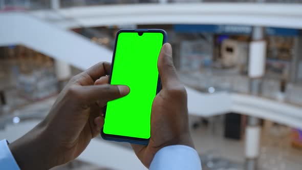 Handheld Camera: Point of View of Man at Shopping Center Using Phone With Green Mock-up Screen