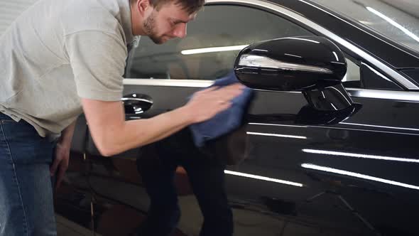 Man Polishes the Car Uses a Microfiber Cloth and Polish To Wipe the Car's Body