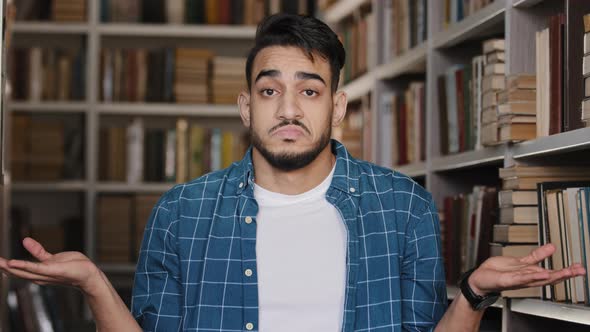 Closeup Young Upset Man Standing Indoors in University Library Hispanic Student Misunderstood