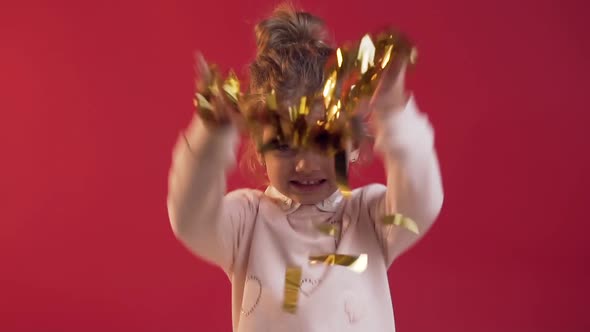 Charming Little Girl with Cute Smile Scattering Confetti on the Red Background