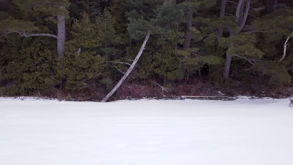 Get an aerial view of Ice Fishing on Fitzgerald Pond, Maine. Fly across the tree line to reveal camp