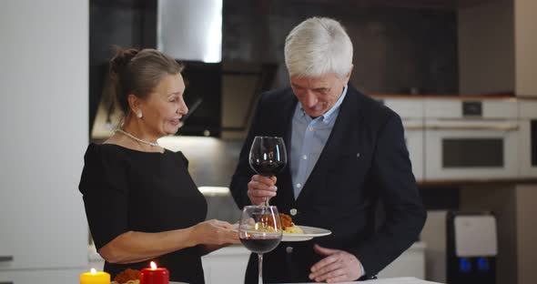 Senior Elegant Couple Drinking Red Wine Having Romantic Dinner at Luxury Kitchen