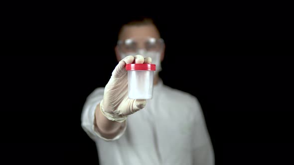 Sperm in a Test Bank Close-up. Man Doctor Holds Out a Jar of Sperm To the Camera on a Black