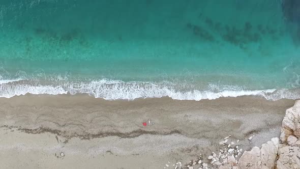 Young Woman Lying On The Back Near The Waves Of Blue Sea