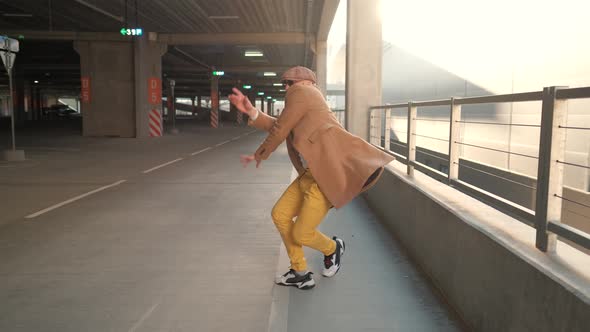 Cheerful and Happy Young Man with Beard Actively Dancing While Walking Down the Street on Sunset