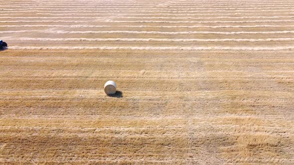 The tractor roll up the straw and releases a packed round bale on agricultural field