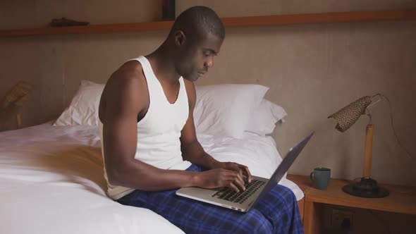 African American using computer in bedroom