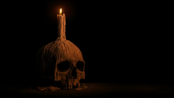 Skull With Melted Candle Burning In The Dark