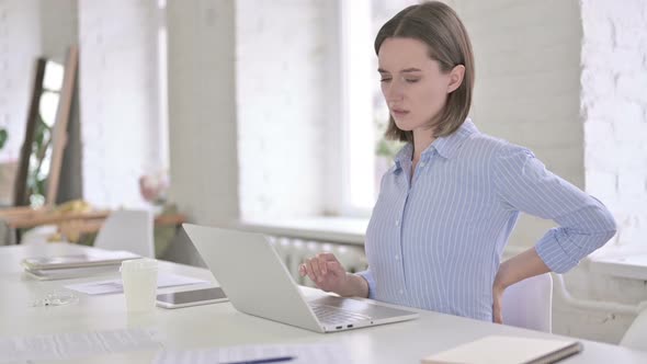 Tired Young Woman Having Back Pain in Modern Office