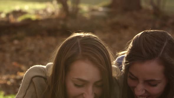 Twin teenage girls laughing as they compare what is on their phones