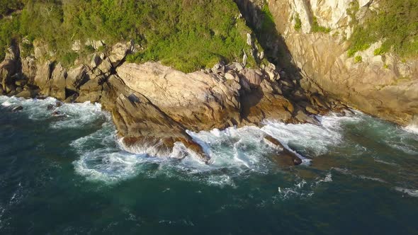 Aerial parallax shot of the rugged coastline on the Trilha da Sepultura at golden hour in Bombinhas