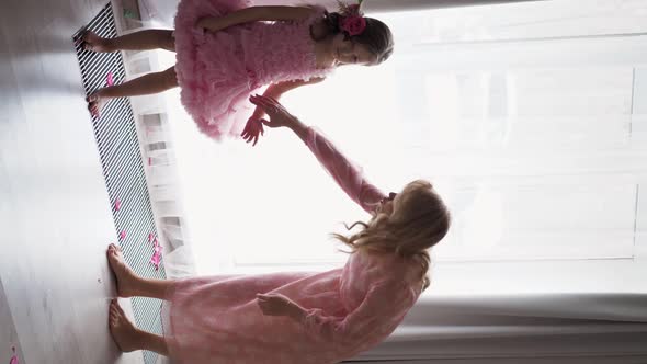 Backstage the Photographer with Beautiful Family Mother and Daughter in Pink Dress Near Large Window