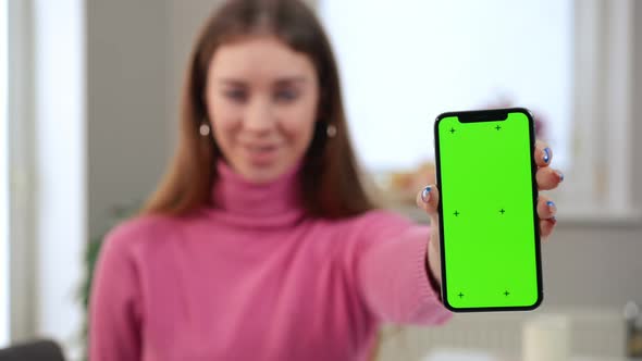Web Mockup Green Screen Smartphone in Hand of Blurred Satisfied Woman Smiling at Background