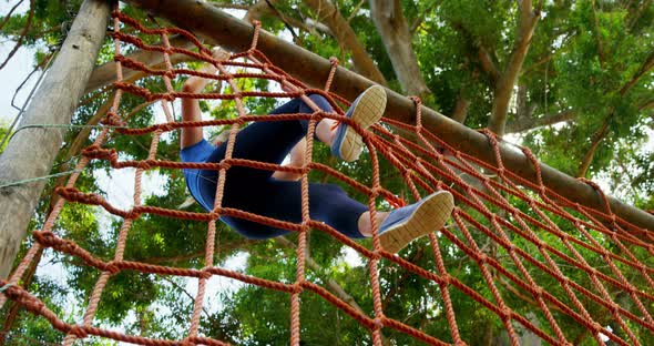 Fit woman climbing a net during obstacle course 4k