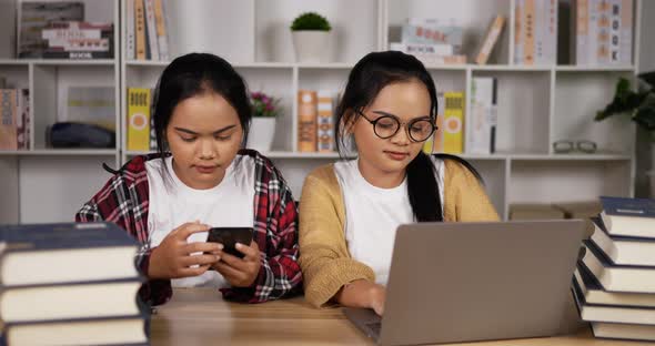 Twin asian girls using laptop and smartphone to learning online