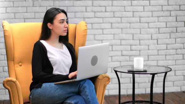 Pensive Asian Freelancer Female Use Laptop Yellow Armchair