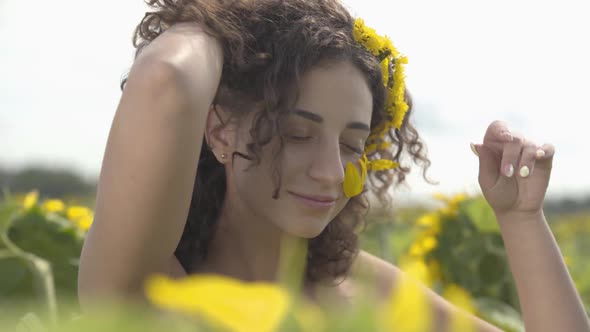 Portrait of Beautiful Curly Playful Girl Looking at the Camera Smiling Standing on the Sunflower