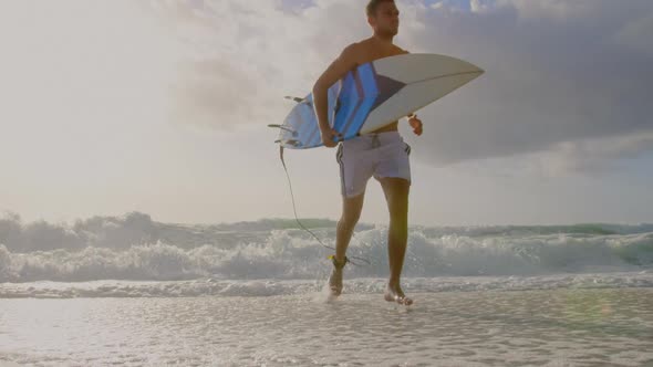 Male surfer running on the beach 4k