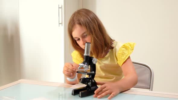 Girl Inserts a Glass Slide Into the Microscope