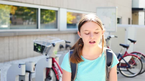 Portrait of irritated fifteen-year-old girl by city bikes