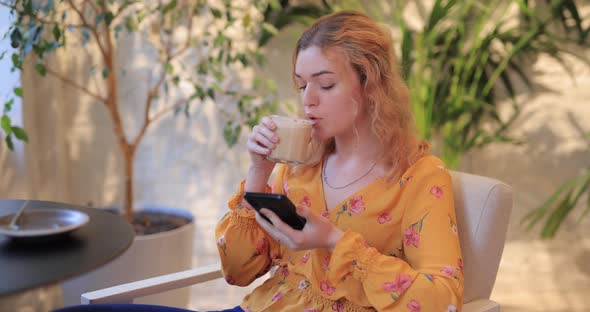 Pretty Woman Using Smart Phone Sitting in a Cafe