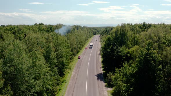 Aerial View of White Truck with Cargo Semi Trailer and Several Cars Moving on Road in the Forest. V2