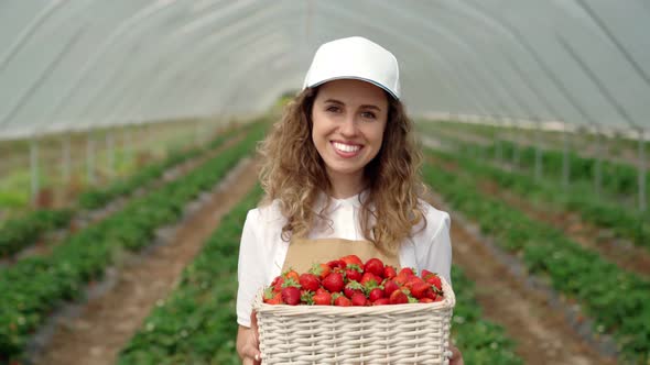 Happy Woman Farmer Smiling and Holding Fresh Strawberry
