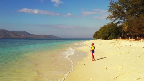 Boy fishing on luxury bay beach journey by blue sea and white sandy background of Gili Trawangan nea