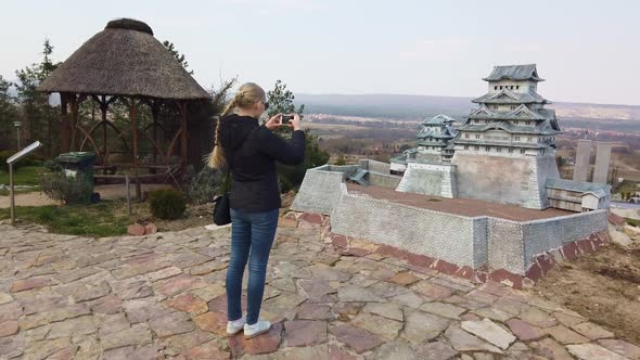 Woman Takes a Photo Near a Miniature Chinese Japanese Pagoda. Park of Miniatures.