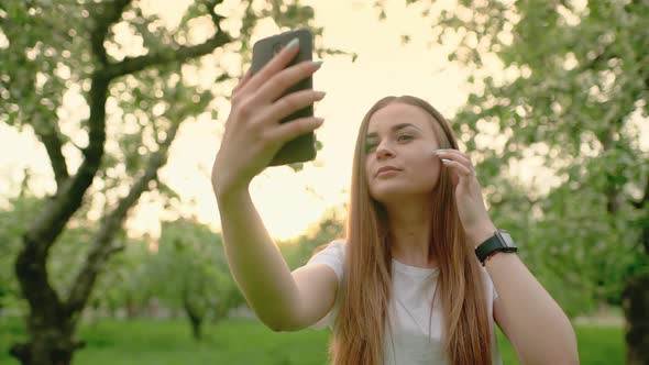 Attractive Blonde Girl Smiling While Taking a Selfie Using a Smartphone