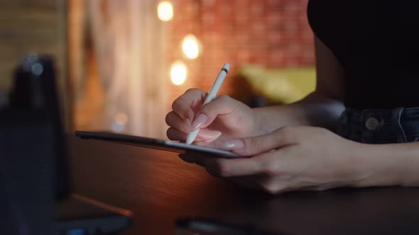 Woman Artist Draws on Graphic Tablet While Sitting at Table Using Stylus Side View Closeup