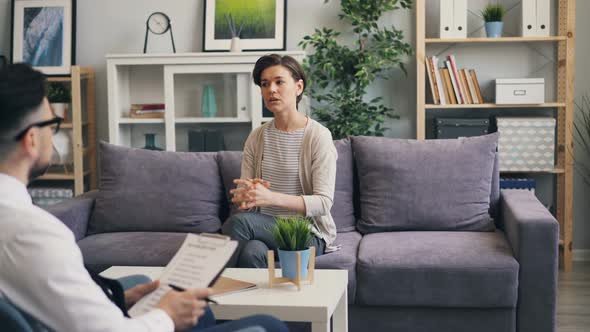 Cheerful Woman Speaking with Psychological Counsellor Sitting on Sofa in Office