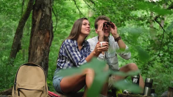 Tourists are Resting Sitting on Log While Hiking in Wood