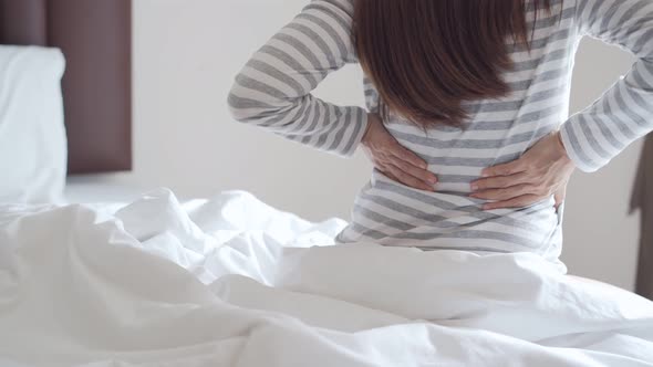 Woman suffering from back ache on the bed in the morning