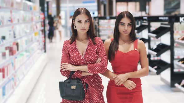 Two Young Beautiful Brunette Women in Red Dresses Posing While Shopping