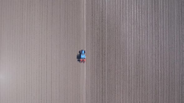 Tractor in a field ploughing, countryside aerial view