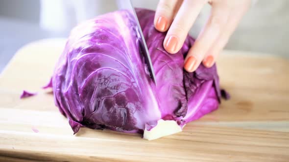 Cutting fresh red cabbage on a wood cutting board.