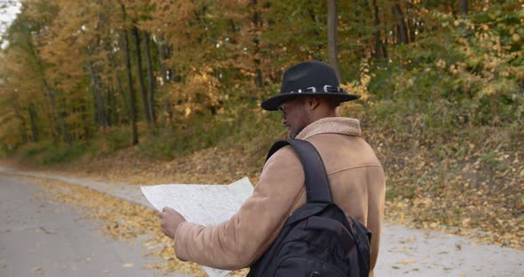 Rear View Young Black Traveler with a Map in Hands