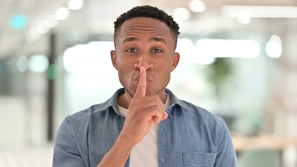 Portrait of Casual African Man Putting Finger on Lips, Quiet Sign 