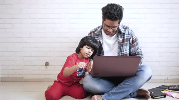 Young Father Working at Laptop at Home with Child
