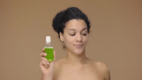 Beauty Portrait of Young African American Woman Holding Mouthwash and Toothbrush Making Choice