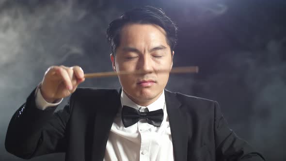 Close Up Of Asian Conductor Man Holding A Baton And Showing Gesture In The Black Studio