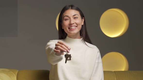 Portrait of a Smiling Asian Female Tenant Showing the Keys to a New Apartment Looking Into the