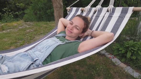 Slow motion shot of smiling woman relaxing in hammock