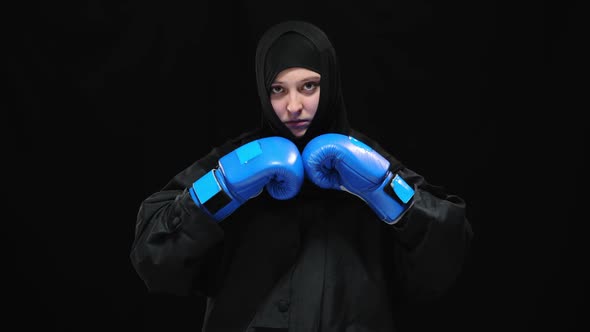 Serious Confident Woman in Hijab Posing at Black Background Wearing Boxing Gloves