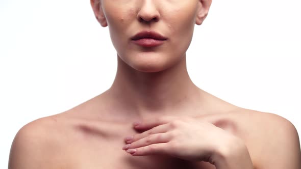 Woman Runs Finger Over Collarbones While Standing in Studio on White Background Closeup Front View