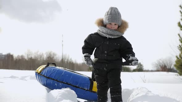 Little Boy Is Walking Pulling Tubing for Slide in Snow in Winter Park