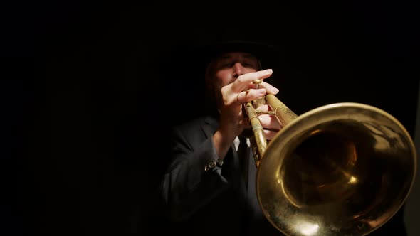 Jazzman Plays in Dark Room on Trumpet Illuminated From Above By Spotlight Front View