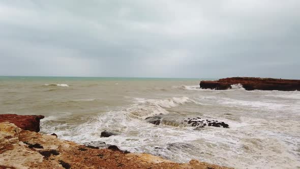 Shot of Sea Waves Are Crashing Into the Rocky Cliffs of an Island Before the Storm