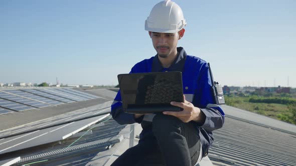 Asian technician inspection solar cell panels field of on roof top factory.